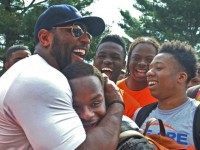 Former Baltimore Ravens NFL football player Ray Lewis hugs 17-year-old Azariah Bratton-Bey Jr., a senior running back on Frederick Douglass High's football team, during a visit to the school Thursday, April 30, 2015, in Baltimore. Lewis, Ravens coach John Harbaugh, and other players visited schools in downtown Baltimore in the aftermath of riots that ravaged the city.