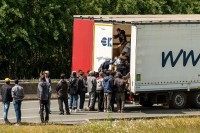 Migrants climb in the back of a lorry on the A16 highway leading to the Eurotunnel on June 23, 2015 in Calais, northern France. Some of the thousands of illegal immigrants camped in Calais and desperately trying to cross the Channel to reach Britain took advantage of a protest by French sailors blocking access roads to the Channel Tunnel on June 23 to climb onto stationery vehicles, said an AFP reporter on the scene.  AFP PHOTO / PHILIPPE HUGUEN
