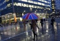 Workers walk in the rain at the Canary Wharf business district in London