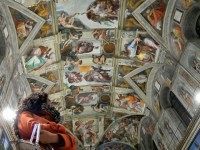 Journalists stare at the Sisitne Chapel with its new lighting during a press visit at the Vatican on October 29, 2014. The Vatican presented the LED lighting in the Sistine Chapel to illuminate the ceiling frescos. It also enstalled a new air-conditioning system and it's planning to put a limit on the number of visitors allowed in. This room where popes have been elected since the mid-15th century is visited by 6 million tourists a year to marvel at Michelangelos ceiling and his depiction of the Last Judgment on the altar wall. AFP PHOTO / Filippo MONTEFORTE / MUSEI VATICANI RESTRICTED TO EDITORIAL USE - MANDATORY CREDIT 'AFP PHOTO / FILIPPO MONTEFORTE © MUSEI VATICANI' - NO MARKETING NO ADVERTISING CAMPAIGNS - DISTRIBUTED AS A SERVICE TO CLIENTS (Photo credit should read FILIPPO MONTEFORTE/AFP/Getty Images)