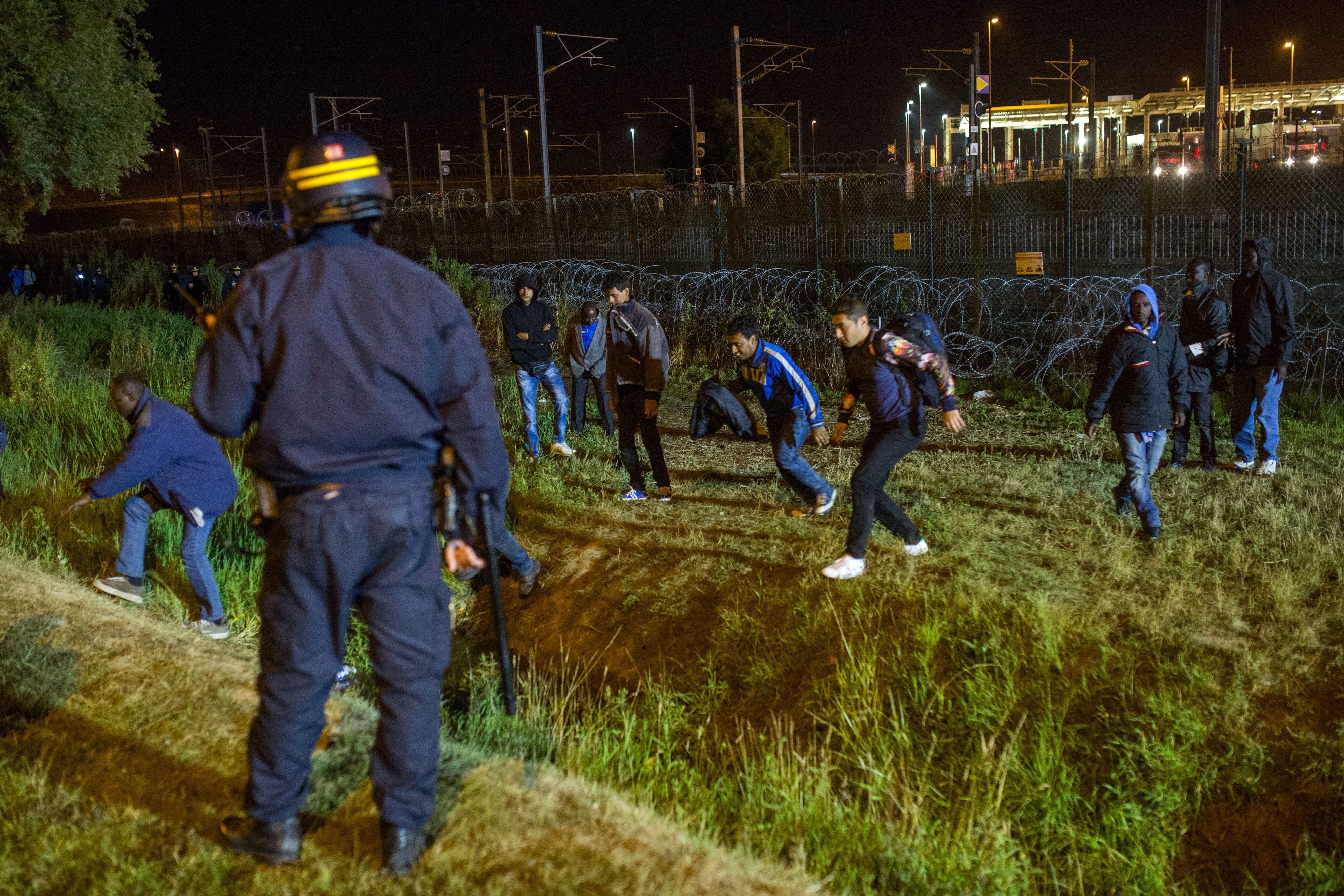 A policeman watches men move away from a security fence beside train tracks (Rob Stothard/Getty Images)