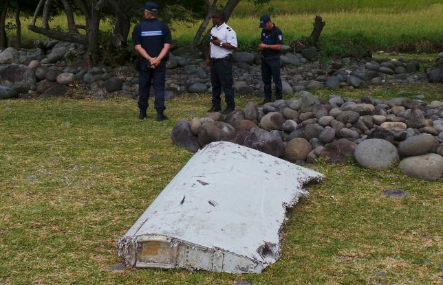 French gendarmes and police stand near a large piece of plane debris which was found on the beach in Saint-Andre, on the French Indian Ocean island of La Reunion