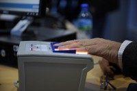 A passenger gets his fingers scanned by