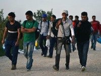 SID, SERBIA - SEPTEMBER 17: Men walk with backpacks as migrants continue to arrive by bus where they walk the final few kilometres from Serbia to Croatia opening up a new route to northern EU countries on September 17, 2015 in Sid, Serbia.