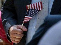 A man holds an American Flag before taking the Oath of Allegiance during a special naturalization ceremony at the Metropolitan Museum of Art on July 22, 2014 in New York City. Over fifty people representing countries from Albania to Burundi took part in the morning ceremony at the American Wing of the museum. The Oath of Allegiance was administered by U.S. Citizenship and Immigration Services (USCIS) Deputy Director Lori L. Scialabba. (Photo by
