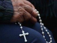 A faithful prays in front of Carondelet presidential palace in Quito, where Pope Francis is expected to make a courtesy visit to Ecuadorean President Rafael Correa, on July 6, 2015. Pope Francis celebrated an open-air mass with than 600,000 people under scorching heat in Guayaquil, Ecuador's largest city, calling for more help for families on his return to his home region. AFP PHOTO / MARTIN BERNETTI (Photo credit should read