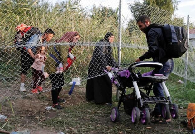 Migrants pass under highway security fence as they try to find a new way to enter Hungary after Hungarian police sealed the border with Serbia near the village of Horgos