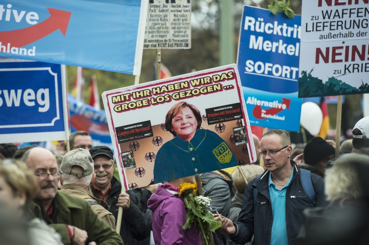 An AfD supporter holds a placard depicting Angela Merkel wearing the uniform of the old Communist "German Free Youth". The text says: "With her we have hit the jackpot..." (JOHN MACDOUGALL/AFP/Getty Image)