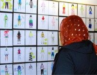 In this June 10, 2015 photo, a woman looks at design drawings for Muslim girls athletic wear before a fashion show in Minneapolis. Muslim girls who play sports have challenges that go beyond the sporting. They worry about tripping on a long, flowing dress, or having a loosely wrapped hijab come undone during a crucial play.
