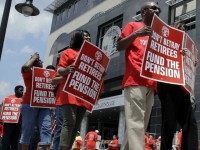 Union members carry protest signs as they march outside the Mercer County Criminal Courthouse before arguments June 25, 2014, over Gov Christie's plan to use pension payments to balance the budget.