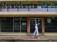 A nun walks in front of a closed furniture store in Lares, Puerto Rico, on September 2, 2015.