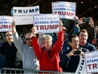 Campaign supporters hold up signs for Republican presidential candidate Donald Trump as his plane arrives to a campaign event at the International Air Response facility on December 16, 2015 in Mesa, Arizona. Trump is in Arizona the day after the Republican Presidential Debate hosted by CNN in Las Vegas, Nevada. (Photo by