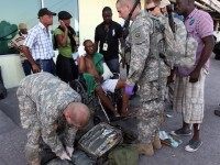 A US Army doctor treats an injured Haitian man at the Port au Prince international airport in Port au Prince on January 15, 2010. The US troops were the first of an estimated 1,000 due to pour into the country over the course of the day. The United States is deploying as many as 10,000 troops to Haiti over the next few days, although many will remain on an armada of naval vessels gathering offshore, led by the aircraft carrier USS Vinson, the Pentagon said. AFP PHOTO / THOMAS COEX (Photo credit should read THOMAS COEX/AFP/Getty Images)