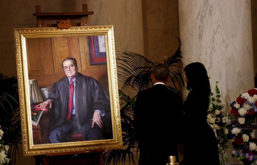 President Obama and First Lady Michelle Obama look at a portrait of Anthony Scalia after paying their respects to Justice Scalia, in front of the casket bearing his body, in the Great Hall of the Supreme Court. (Photo by Aude Guerrucci/Getty Images)