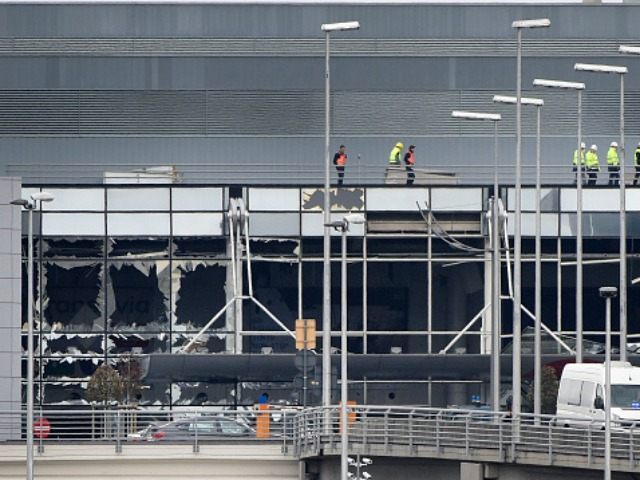 Workers walk on the roof of the damaged facade of Brussels airport in Zaventem on March 23, 2016
