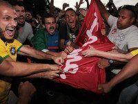 Anti-government protestors try to rip apart a Workers' Party flag during a demonstration outside Planalto presidential palace as they demand the impeachment of Brazil's President Dilma Rousseff in Brasilia, Brazil, Thursday, March 17, 2016. Rousseff's critics accuse her of a transparent maneuver aimed at helping her mentor, the once wildly popular former President Luiz Inacio Lula da Silva, slalom legal woes that saw him taken in for questioning in a sprawling corruption probe less than two weeks ago. Cabinet members cannot be investigated, charged or imprisoned unless authorized by the Supreme Court. (AP Photo/Joedson Alves)