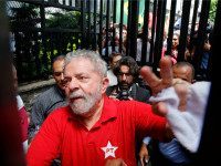 Brazil's former President Luiz Inacio Lula da Silva greets supporters who have gathered outside his residence, in Sao Bernardo do Campo, in the greater Sao Paulo area, Brazil, Saturday, March 5, 2016. Brazilian police hauled in the former president for questioning Friday, in a sprawling corruption case centered on the Petrobras oil company that has already ensnared some of the country's top lawmakers and richest and most powerful businessmen. Silva reacted with indignation, saying the Petrobras corruption case has become a political witch hunt targeting him and his governing Workers' Party. (AP Photo/Andre Penner)