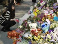A woman visits a makeshift memorial for a girl who was attacked to death Monday by a knife-wielding assailant outside a subway station in Taipei, Taiwan, Tuesday, March 29, 2016. A transit police officer was stabbed in the head at another subway station in the city Tuesday, a day after a 3-year-old girl was decapitated in apparently random knife attacks in Taiwan's capital. (AP Photo/Chiang Ying-ying)
