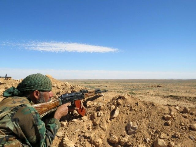 A Syrian army soldier takes aim from a position on the outskirts of Syria's Raqa region on February 19, 2016