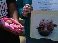 An anti-abortion activist holds a model of a fetus next to an image reportedly of an aborted fetus during a protest outside of the Longworth House Office Building on Capitol Hill in Washington, DC on May 7, 2015.