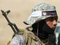An Iraqi Shiite fighter from the Popular Mobilisation units, fighting alongside Iraqi forces, stands wearing an Islamic headband bearing portraits of Iran's supreme leader, Ayatollah Ali Khamenei (L) and late Shiite cleric Ayatollah Mohammed Sadeq al-Sadr, assassinated by the regime of former Iraqi leader Saddam Hussein in 1999, during a military operation against Islamic State (IS) group jihadists in the centre of Baiji, some 200 kilometres north of Baghdad on October 18, 2015. Iraqi forces advanced on three fronts against the Islamic State group, flushing out pockets of resistance in and around Baiji and closing in on Ramadi and Hawijah, officers said. AFP PHOTO / AHMAD AL-RUBAYE (Photo credit should read AHMAD AL-RUBAYE/AFP/Getty Images)
