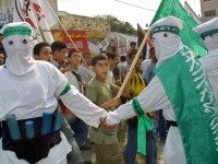 Masked Hamas militants, dressed as 'martyrs' for an honor guard while wearing mock ups of a suicide-bomber's 'belt of explosives' during the funeral of his slain leader Abdel Rahman Hamad October 14, 2001 in the West Bank town of Qalqilya, hours after the Islamic activist was gunned down by Israeli special forces.
