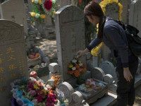 CHINA, BEIJING : TOPSHOT - A woman pours alcohol over a grave during the "Qingming" festival, or Tomb Sweeping Day, at a cemetary in Babaoshan in Beijing on April 4, 2016. During Qingming, Chinese traditionally tend the graves of their departed loved ones and often burn paper offerings to honour them and keep them comfortable in the afterlife. / AFP / FRED DUFOUR