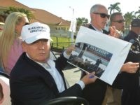 GOP presidential candidate Donald Trump shows a photograph a supporter wants him to sign, during the final round of the Cadillac Championship golf tournament, Sunday, March 6, 2016, in Doral, Fla.
