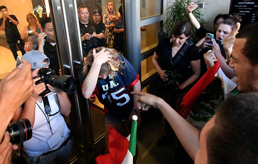 A woman wearing a Trump shirt (C) is pelted with eggs by protesters while pinned against a door near where Republican presidential candidate Donald Trump holds a rally in San Jose, California on June 02, 2016. Protesters attacked Trump supporters as they left the rally, burned an american flag, trump paraphernalia and scuffled with police and each other. / AFP / JOSH EDELSON (Photo credit should read JOSH EDELSON/AFP/Getty Images)