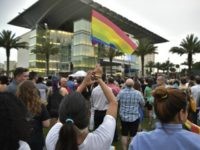 A woman holds a rainbow flag at a vigil for the victims of the Pulse nightclub shooting, on June 13, 2016 at the Dr. Phillips Center for the Performing Arts in Orlando, Florida.