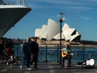 A man plays a song on a guitar on the Sydney Harbour in front of iconic Opera House on May 11, 2016. Australia's jobless rate was at 5.7 percent in March, but is forecast by the government in its annual national budget unveiled last week to fall to 5.5 percent in 2016-17. / AFP / SAEED KHAN (Photo credit should read SAEED KHAN/AFP/Getty Images)