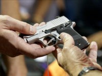 A gun seller shows a SIG Sauer hand gun to a customer at a gun show hosted by Florida Gun Shows, Saturday, Jan. 9, 2016, in Miami. Schlesinger purchased an Uzi and a Smith & Wesson 38. (AP Photo/Lynne Sladky)
