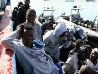 Illegal migrants sit on the dock at the Tripoli port after 115 migrants of African origins were rescued by two coast guard boats at sea when their boat started sinking off the Libyan coast on April 11, 2016.