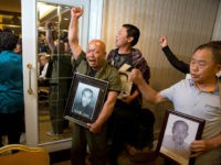 Ma Wenyi, center, holding a photo of his father who was forced to work during World War II at a mine for Mitsubishi Mining Corp., shouts as he demands to join a press conference in Beijing Wednesday, June 1, 2016. Mitsubishi Materials Corp., one of dozens of Japanese companies that used Chinese forced laborers during World War II, reached a settlement with thousands of victims on Wednesday that includes compensation and an apology. (AP Photo/Ng Han Guan)