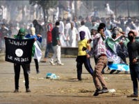 SRINAGAR, INDIA - SEPTEMBER 25: Kashmiri Muslim protesters throw stone as they carry a ISIS flag and portraits of local militants as tear gas shells exploded near them during the clashes between protesters and security men on September 25, 2015, in Srinagar, India. Kashmir valley witnessed restrictions with the government snapping internet services and placing separatist leaders under house arrest fearing anti-government protests over the decision of the Jammu & Kashmir High Court calling for implementing a ban on the sale of beef in the state and stopping of cow slaughter. Muslims on Eid al-Adha slaughter cattle, sheep and goats as a part of the Prophet Abrahamic tradition. (Photo by Abid Bhat/Hindustan Times via Getty Images)