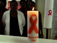 November 28, 2013 shows staff members of the Themba Lethu Clinic in Johannesburg, the largest antiretroviral treatment site in the country, posing behind candles commemorating World Aids Day (December 1). South Africa has been hailed as a model for HIV treatment, but some now fear its very success may be breeding complacency and making people less careful about infection. AFP PHOTO / ALEXANDER JOE (Photo credit should read