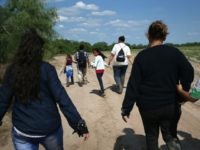 Central American immigrant families walk through the countryside after crossing from Mexico into the United States to seek asylum on April 14, 2016 in Roma, Texas.