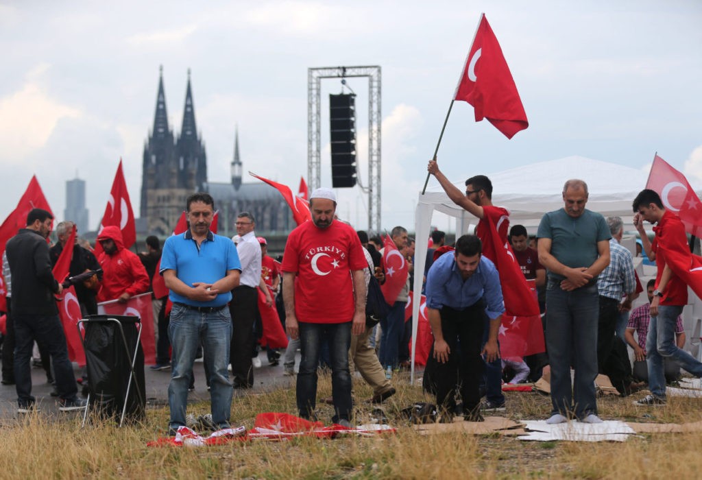Supporters of Turkish President Recep Tayyip Erdogan pray ahead of a rally on July 31, 2016 in Cologne, as tensions over Turkey's failed coup put authorities on edge. Police said some 20,000 people had joined in the demonstration staged by groups including the pro-Erdogan Union of European-Turkish Democrats (UETD). / AFP / DPA / Oliver Berg / Germany OUT (Photo credit should read OLIVER BERG/AFP/Getty Images)