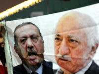 TURKEY, Istanbul : A Turkish protester (L) holds up a banner with pictures of Turkish Prime Minister Recep Tayyip Erdogan (C) and the United States-based Turkish cleric Fethullah Gulen (R) during a demonstration against goverment on December 30, 2013 in Istanbul. Erdogan lashed out at the judiciary as he tried to tamp down a corruption probe that has shaken his government and sparked a new wave of anti-government protests. The conservative prime minister, who has dug in his heels over the crisis that has led to the resignation of three ministers, went again on the attack during a speech in the southern city of Manisa. AFP PHOTO / OZAN KOSE