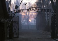 Main gate entering the Nazi Auschwitz death camp at sunrise with the infamous sign reading "Arbeit macht frei" (Work sets you free)