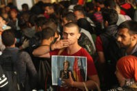 MUNICH, GERMANY - SEPTEMBER 05: A migrant from Syria holds a picture of German Chancellor Angela Merkel as he and approximately 800 others arrive from Hungary at Munich Hauptbahnhof main railway station on September 5, 2015 in Munich, Germany. Thousands of migrants are traveling to Germany following an arduous ordeal in Hungary that resulted in thousands walking on foot and then being bussed by Hungarian authorities from Budapest to the Austrian-Hungarian border.  (Photo by Sean Gallup/Getty Images)