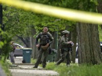 Chicago SWAT officers gather outside a house after rushing the structure where a man suspected of killing a few people had barricaded himself and fired shots at officers on the south side of Chicago on Thursday, May 12, 2016. After hours in a standoff with a man suspected of killing a few people, Chicago Police SWAT officers rushed into the house Thursday afternoon to find the man had apparently shot himself. (AP Photo/M. Spencer Green)