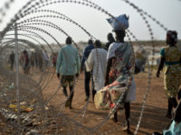 FILE - In this Tuesday, Jan. 19, 2016 file photo, displaced people walk next to a razor wire fence at the United Nations base in the capital Juba, South Sudan. According to reports from victims which have come to light Monday Aug. 15, 2016, South Sudanese troops, fresh from winning a battle against opposition forces in the capital, Juba, on July 11, 2016, went on a nearly four-hour rampage through a residential compound popular with foreigners, and the U.N. peacekeeping force stationed nearby are accused of refusing to respond to desperate calls for help. (AP Photo/Jason Patinkin, File)