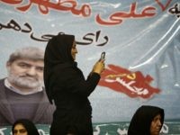 An Iranian woman takes pictures with her mobile phone in front of a portrait of Ali Motahari, a candidate for the upcoming parliamentary elections, during a campaign meeting in Tehran on February 23, 2016. Iranians go to the polls on February 26, 2016 to elect a new 290-seat parliament and the powerful Assembly of Experts which supervises the work of supreme leader Ayatollah Ali Khamenei. / AFP / BEHROUZ MEHRI (Photo credit should read BEHROUZ MEHRI/AFP/Getty Images)