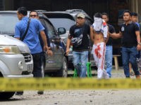 INDONESIA, MEDAN : Indonesian policemen guard a blindfolded suspect who attacked a priest in Medan on August 28, 2016. A knife-wielding attacker in Indonesia stabbed a Catholic priest and tried to set off an explosive device at a church on, police said, the latest in a string of attacks on religious minorities in the mainly Muslim country. / AFP PHOTO / STR