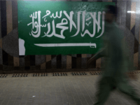A man walks beside the Saudi flag at the popular market of Qabil street in the heart of Jeddah historic center on December 9, 2015 in Jeddah, Saudi Arabia. The street which is one of the oldest business streets that dates back to early days of 20th century, got its name from the Qabil family that owned land originally.