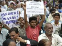 An Indian member of the Dalit caste community holds a placard reading, "In Gujarat, Cow Slaughter is a Sin while Killing Dalits is pardonable" (L) as he participates in a protest rally against an attack on Dalit caste members on July 31, 2016
