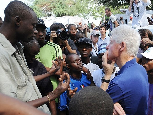 Former US president and UN Special Envoy for Haiti Bill Clinton (R) listens to local residents on October 6, 2010 in a city camp in Port-au-Prince. The Clinton Foundation announced that it will, through its Haiti Relief Fund - provide 500,000 USD in bridge funding for a camp in Petionville run by the J/P Haitian Relief Organization. "Rebuilding housing for more than 1 million people displaced by the earthquake will take time, as teams on the ground continue to clear rubble and build infrastructure, including water and sanitation systems," President Clinton said. AFP PHOTO/ Thony BELIZAIRE (Photo credit should read THONY BELIZAIRE/AFP/Getty Images)