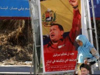 A Lebanese Shiite woman, holding a picture of Hassan Nasrallah, the Secretary General of Hezbollah, walks in front of a poster showing Venezuela's President Hugo Chavez and a slogan that reads: "Gracias Chavez" 21 September 2006 at the southern suburb of Beirut. Chavez stunned the UN General Assembly with a speech in which he called US President George W. Bush "the devil" who acts like he owns the world. Hezbollah supporters headed towards the Lebanese capital for a massive "victory" rally after the devastating war with Israel amid suspense over whether the group's chief Hassan Nasrallah will emerge from hiding.   AFP PHOTO/HASSAN AMMAR        (Photo credit should read HASSAN AMMAR/AFP/Getty Images)
