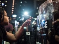 CHARLOTTE, NC - SEPTEMBER 21: With blood covering her hand and arm, a woman points at a police officer on September 21, 2016 in Charlotte, NC. The North Carolina governor has declared a state of emergency in the city of Charlotte after clashes during protests in the city in response to the fatal shooting by police officers of 43-year-old Keith Lamont Scott at an apartment complex near UNC Charlotte. (Photo by Sean Rayford/Getty Images)